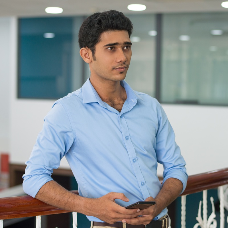 serious pensive young man with smartphone leaning on railing